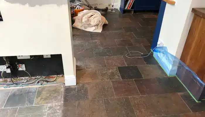 Slate floor exhibiting darker walkway areas and uneven colour across the tiles